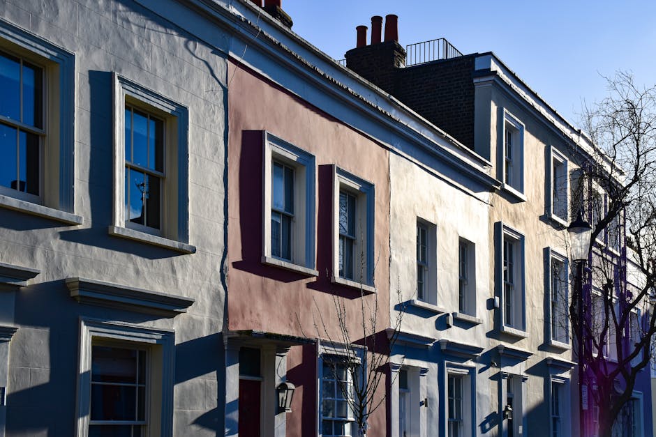 Photograph of a residential townhouse on Regency Street in Westminster, showing a row of three-story buildings with varied pastel-colored facades in white, pink, and cream. The buildings feature multi
