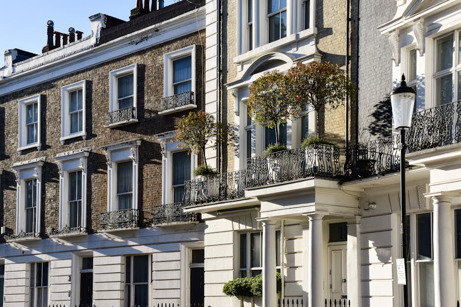 Photograph of a residential townhouse on Regency Street in Westminster, showing a row of three-story buildings with varied pastel-colored facades in white, pink, and cream. The buildings feature multi